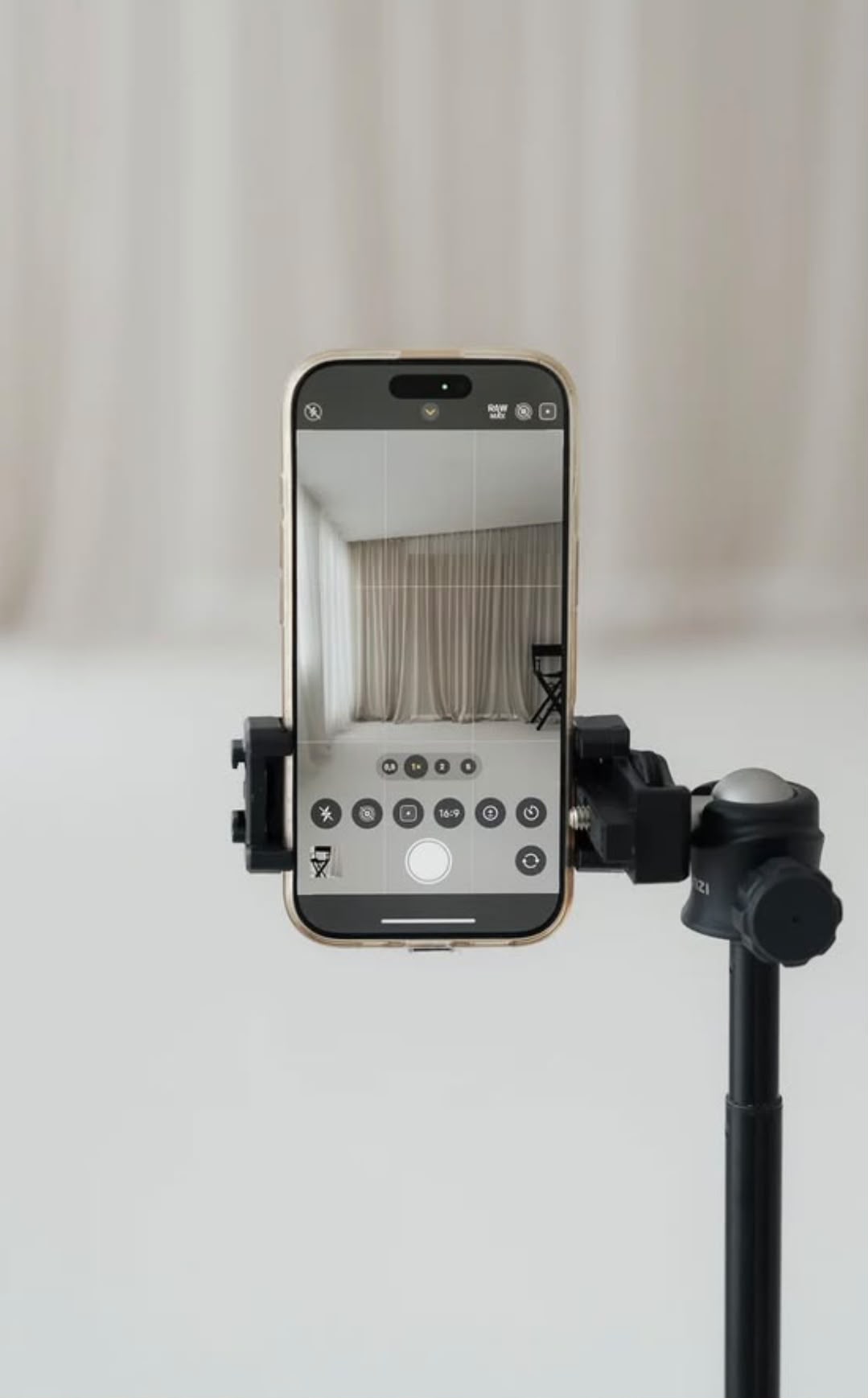 Celular en un trípode preparado para grabar contenido en un estudio claro.